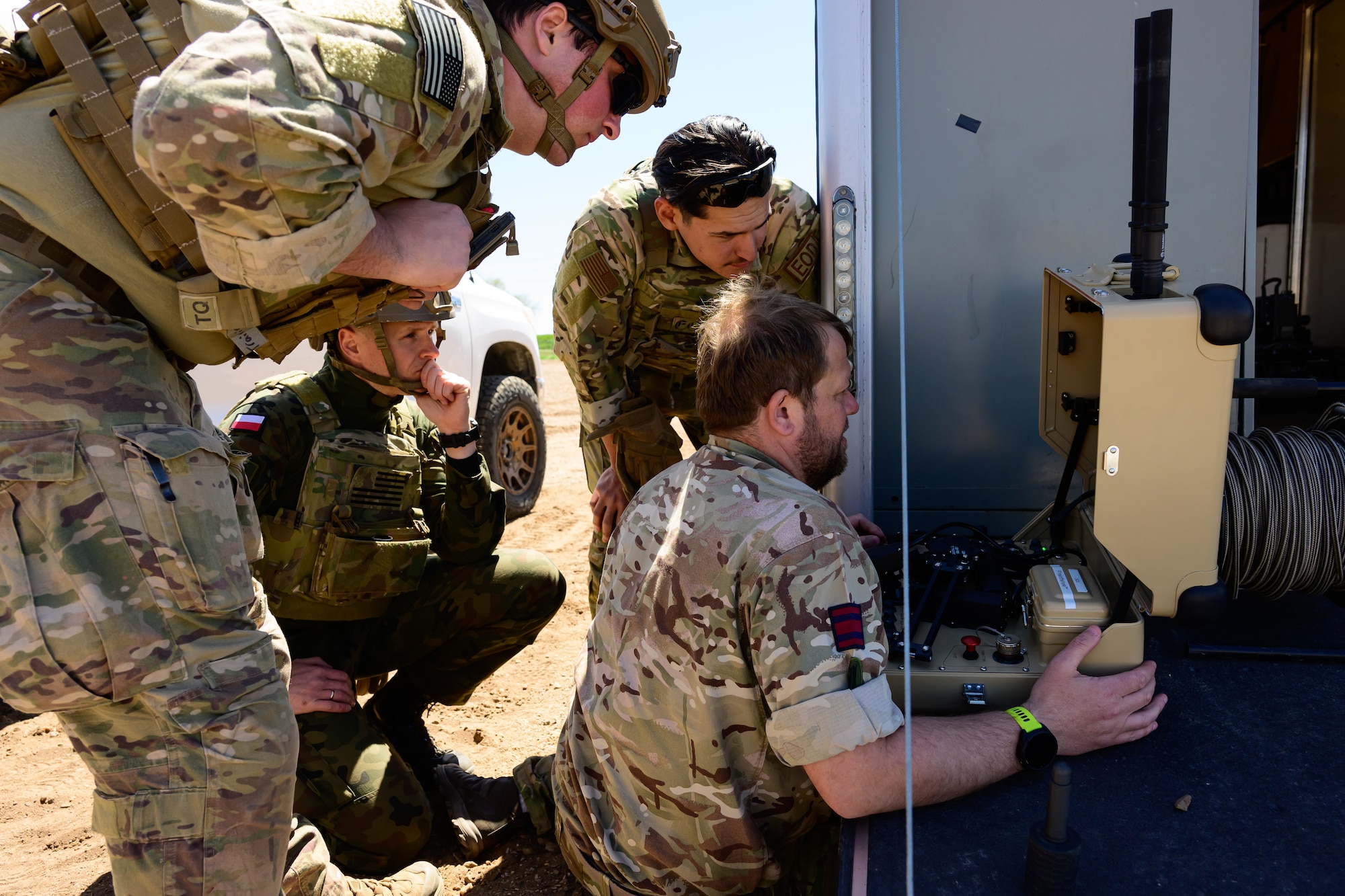 Four military members look at a piece of equipment