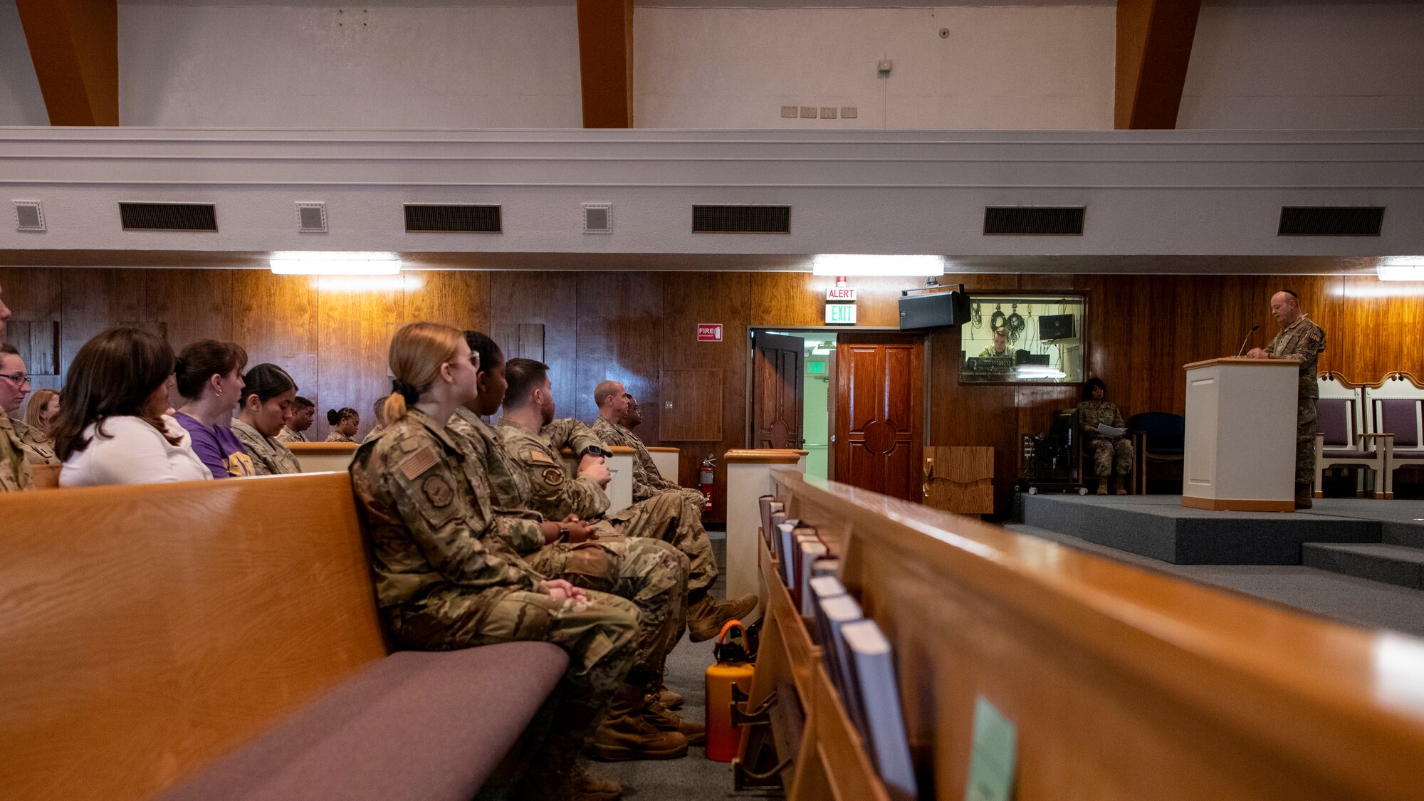 A military chaplain stands in front of a crowd of Airmen and civilians.