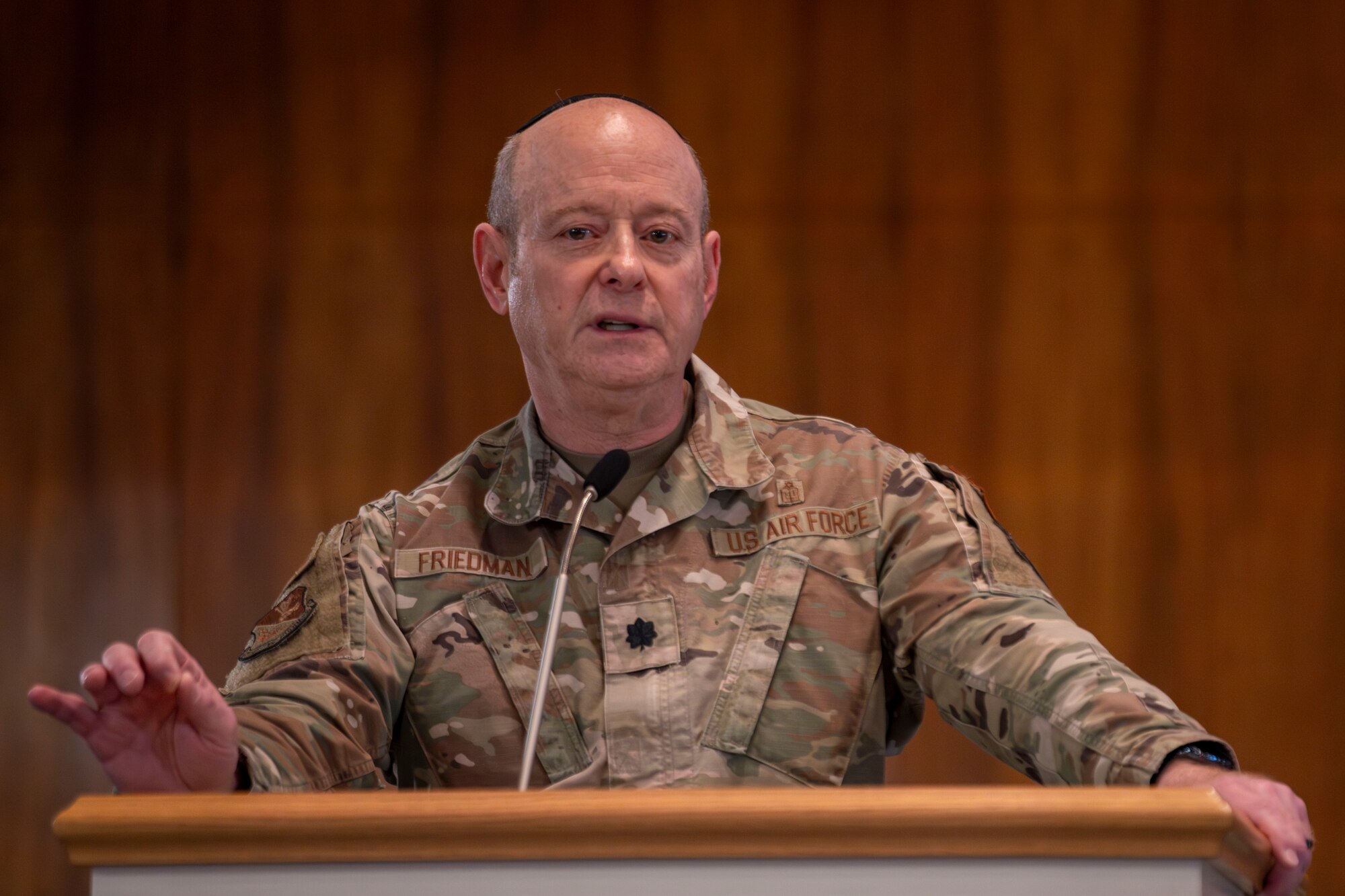 A military chaplain stands behind a podium while giving remarks.