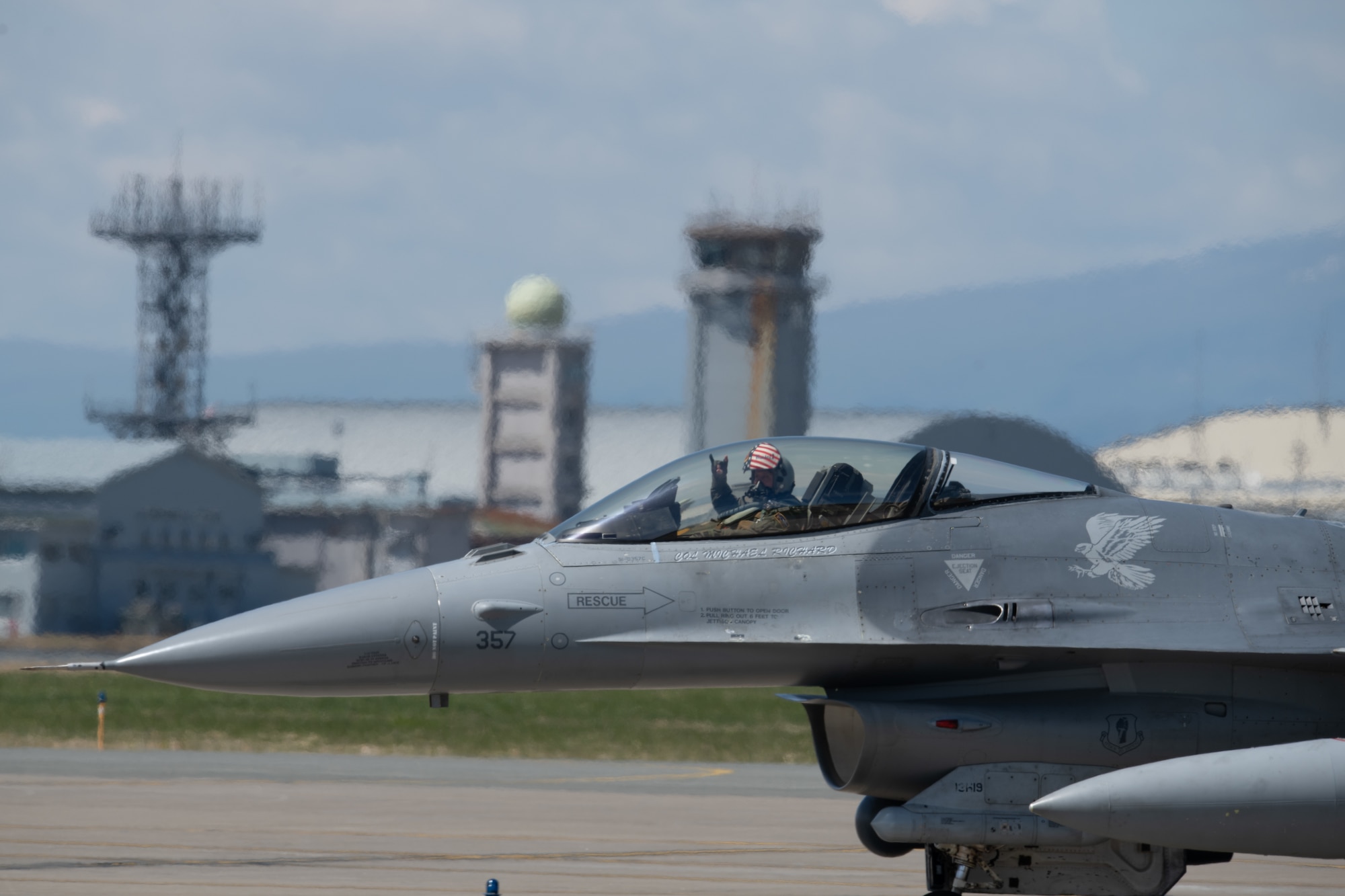 An F-16 fighter pilot in his cockpit waves to the camera