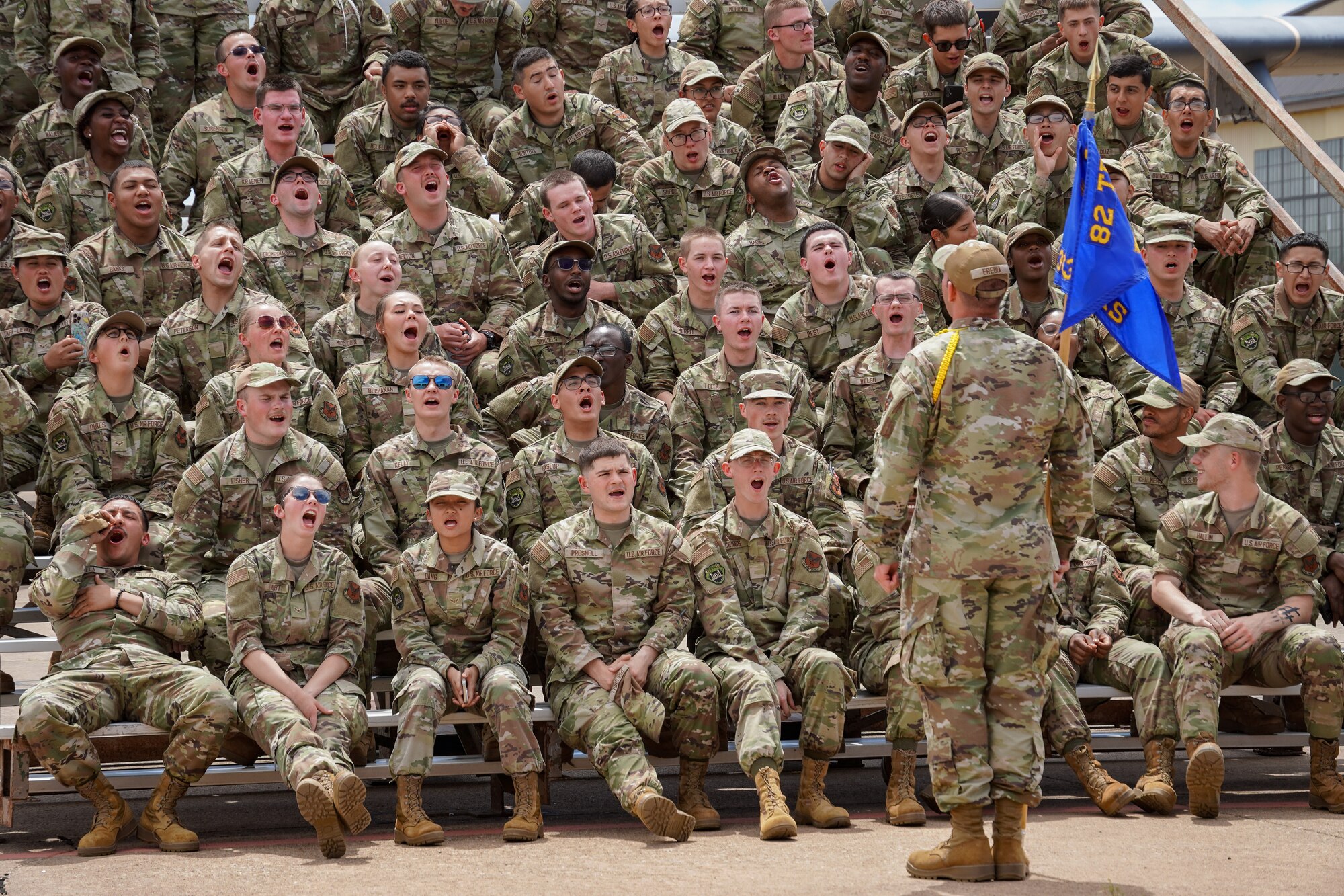Airmen sit in a crowd on bleachers