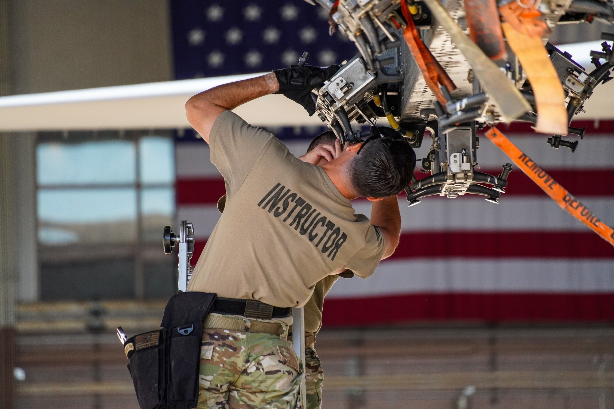 An Airman works on a jet bomb rack