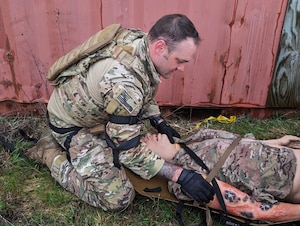 U.S. Air Force Master Sgt. Matthew Vandermolen, explosive ordnance disposal technician with the Wisconsin Air National Guard’s 115th Fighter Wing, prepares to transport an injured patient during a tactical combat casualty care exercise April 18, 2024, at Volk Field Air National Guard Base near Camp Douglas, Wisconsin. The training exercise was part of a 40 hour Tactical Combat Casualty Care - Combat Life Savers Course administered by members of the Wisconsin Air National Guard’s 115th Medical Group to Airmen within the wing who's career fields require advanced lifesaving skills. (U.S. Air National Guard photo by Senior Master Sgt. Paul Gorman)