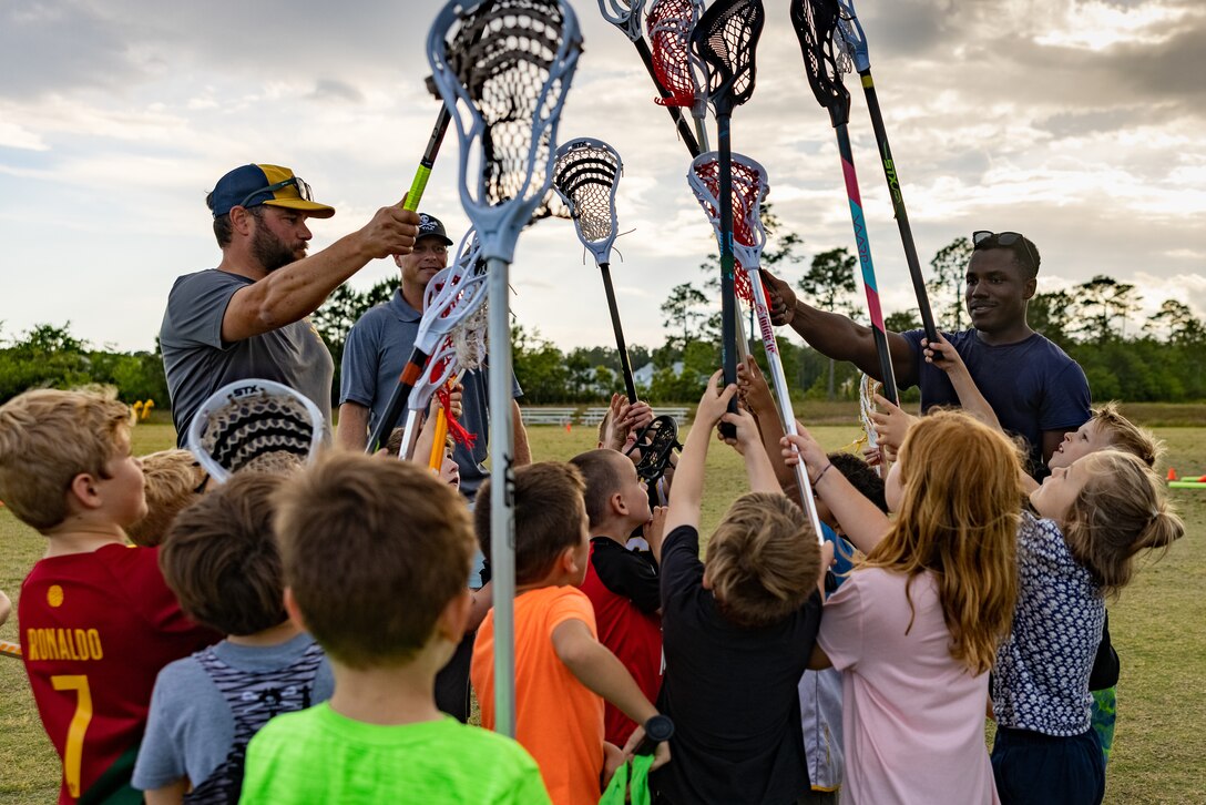 U.S. Marine Corps 2nd Lt. Jalen Harris, right, a Lansdale, Pennsylvania native and an assistant supply officer with Headquarters Battalion, 2d Marine Division, holds a group huddle with members of the Topsail Youth Lacrosse Association after practice in Topsail, North Carolina, May 1, 2024. Volunteering with local sports teams allows Marines to connect and give back to their communities by mentoring the local youth. (U.S. Marine Corps photo by Cpl. Alexis Sanchez)