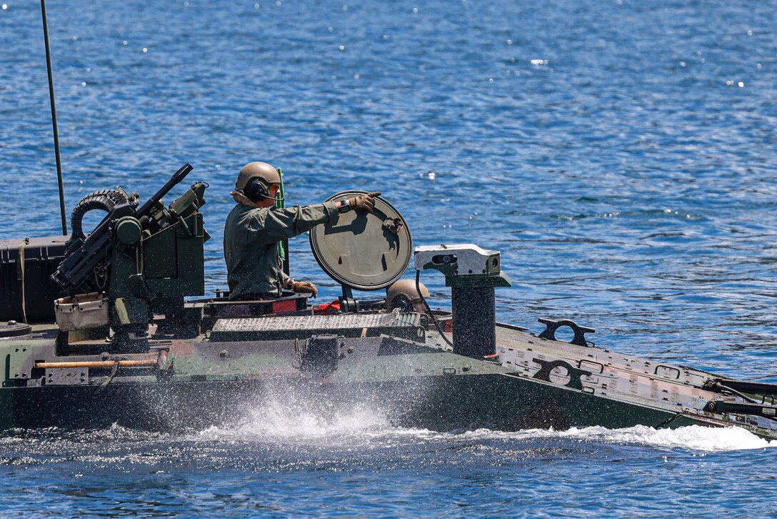 A U.S. Marine assigned to Alpha Company, Battalion Landing Team 1/5, 15th Marine Expeditionary Unit, directs his section of amphibious combat vehicles to the consolidation zone after a waterborne gunnery live-fire training during Exercise Balikatan 24 in Oyster Bay, Philippines, May 4, 2024. BK 24 is an annual exercise between the Armed Forces of the Philippines and the U.S. military designed to strengthen bilateral interoperability, capabilities, trust, and cooperation built over decades of shared experiences. (U.S. Marine Corps photo by Cpl. Aidan Hekker)