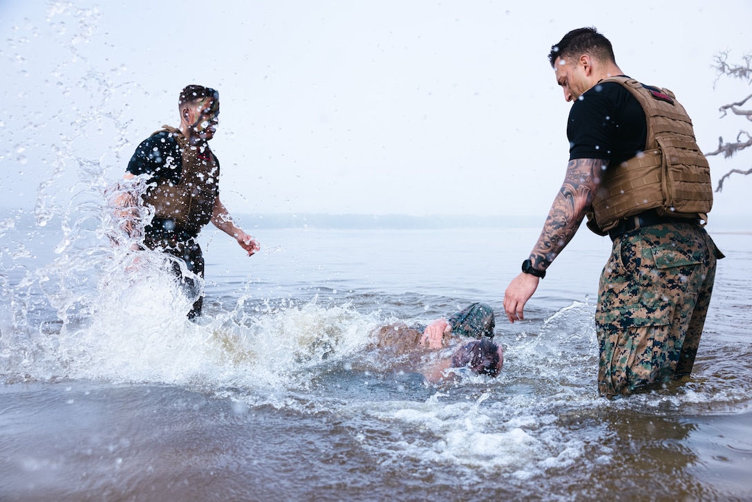 U.S. Marine Corps 1st Lt. Stewart Spurry, left, an infantry officer with 2nd Battalion, 2nd Marine Regiment, 2nd Marine Division, and Staff Sgt. Cesar Menendezlozano, right, a martial arts instructor trainer with the 22nd Marine Expeditionary Unit, II Marine Expeditionary Force, oversee Marines grappling in water during the culmination of Martial Arts Instructor Course (MAIC) 72-24 on Marine Corps Base Camp Lejeune, North Carolina, May 2, 2024. After three weeks of academic classes, advanced martial arts training and pushing their mental grit and physical toughness, Marines graduating MAIC 72-24 earned their ability to lead others in the Marine Corps Martial Arts Program. (U.S. Marine Corps photo by Lance Cpl. Loriann Dauscher)