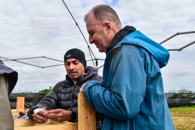 Two people work outside at a soil sifting station.