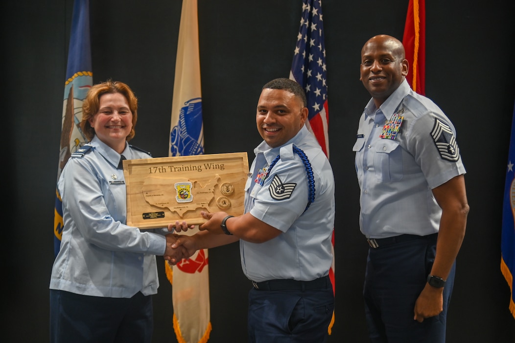 U.S. Air Force Col. Angelina Maguinness, 17th Training Wing commander, shakes hands and poses with Tech Sgt. Corey Hollington, 533rd Training Squadron Detachment 1 military training leader, as he stands next to Chief Master Sgt. Derrick Sherrod, 17th Mission Support Group senior enlisted leader, as he receives his Raider Excellence Service Member of the Quarter award at the Powell Event Center, Goodfellow Air Force Base, Texas, May 3, 2024. The quarterly awards honor individuals for their achievements in the wing. (U.S. Air Force photo by Airman James Salellas)