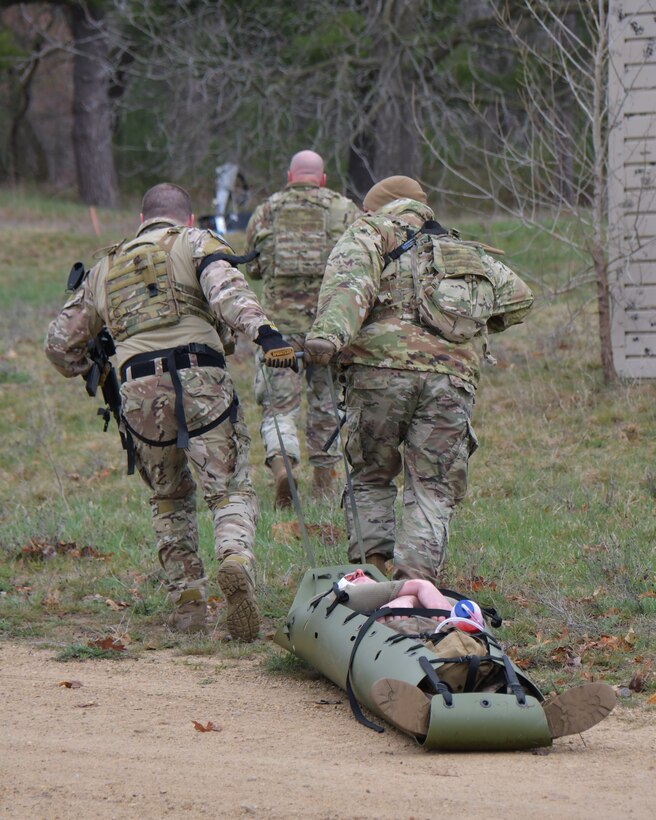 U.S. Air Force security forces and explosive ordnance disposal specialists assigned to the Wisconsin Air National Guard's 115th Fighter Wing transport a wounded patient during a tactical combat casualty care scenario April 18, 2024, at Volk Field Air National Guard Base near Camp Douglas, Wisconsin. TCCC implements proven medical practices in battlefield trauma care and provides basic lifesaving techniques to wounded personnel, substantially increasing battlefield survivability. (U.S. Air National Guard photo by Senior Master Sgt. Paul Gorman)