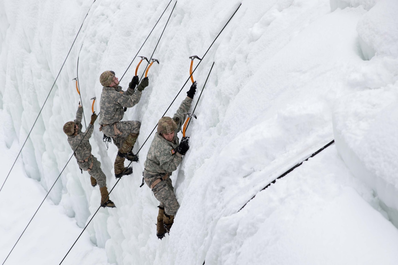 Three men climb a wall of ice using crampons and ice axes.