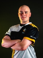 Man with a black and white polo standing in front of an illuminated black background.