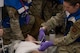 An Airman assigned to the 5th Medical Group (5th MDG) cuts off a patient's shirt during a simulated exercise at Minot Air Force Base, North Dakota, May 8, 2024. The exercise tested the 5th MDG’s readiness to respond to a real-life scenario. (U.S. Air Force photo by Airman 1st Class Trust Tate)