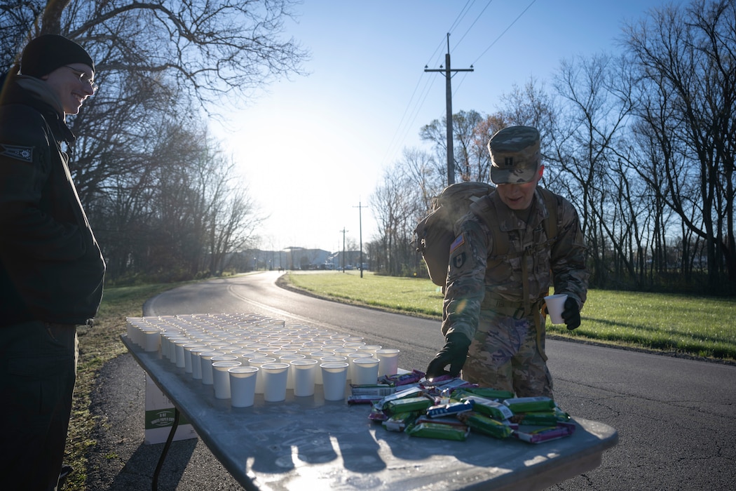 A soldier in uniform grabs a water and snack at the 6-mile marker of the Norwegian Foot March.