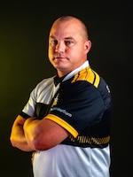 Man with a short-sleeved polo standing in front of a black background.