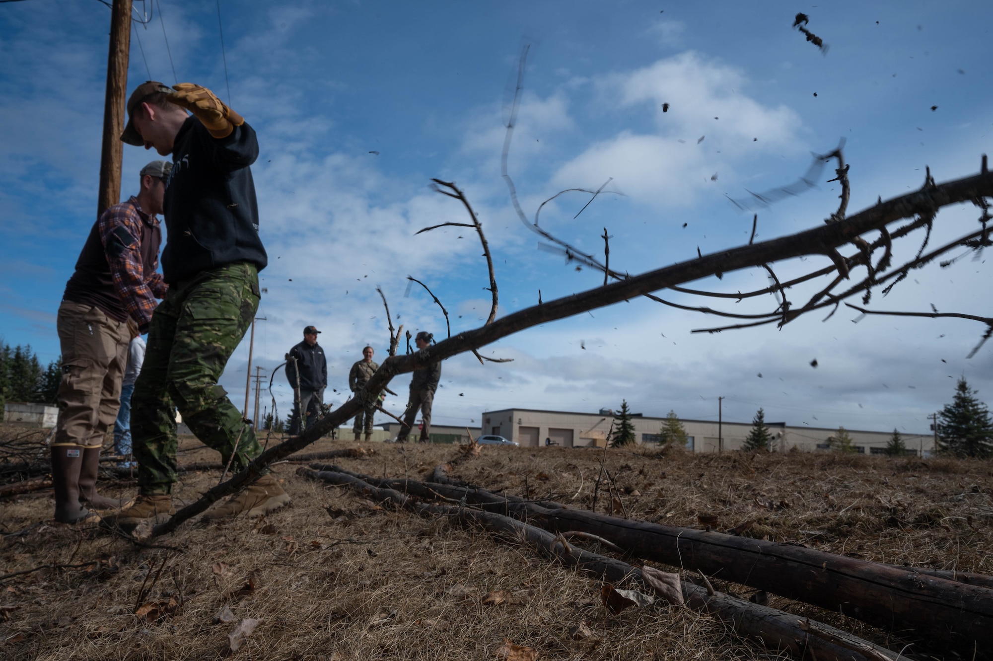 U.S. Air Force Airmen 1st Class Luke Scampone (front), 354th Munitions Support Squadron armament systems journeyman, and Mariano Grovas-Mendez (back), 354th Force Support Squadron financial management technician, break apart a tree branch to transport it during a volunteer event at Eielson Air Force Base, Alaska, May 1, 2024.