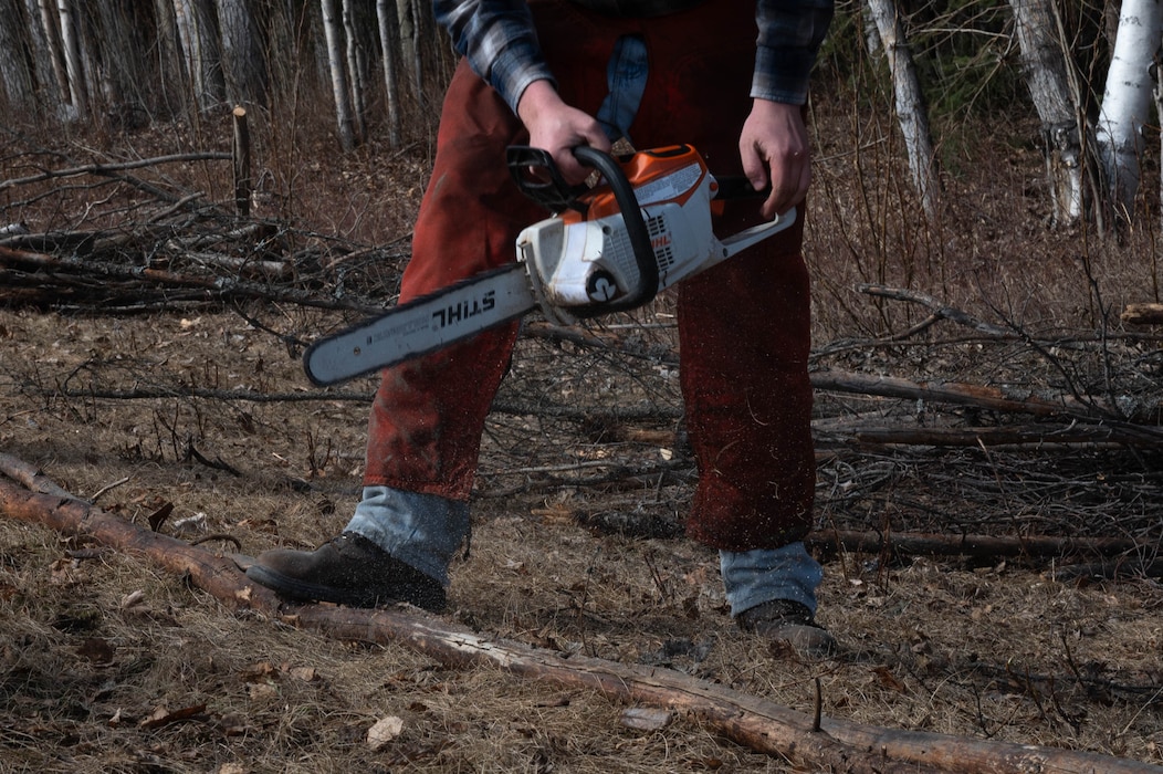 Corey Clements, a wildlife biologist with the Natural Resources Office, prepares to cut a tree branch in preparation for disposal during a volunteer event at Eielson Air Force Base, Alaska, May 1, 2024.