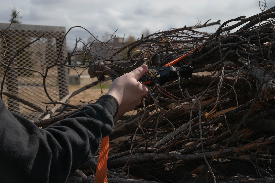 U.S. Air Force Airman 1st Class Luke Scampone, 354th Munitions Support Squadron armament systems journeyman, ties down tree branches on a trailer as part of a volunteer program at Eielson Air Force Base, Alaska, May 1, 2024.