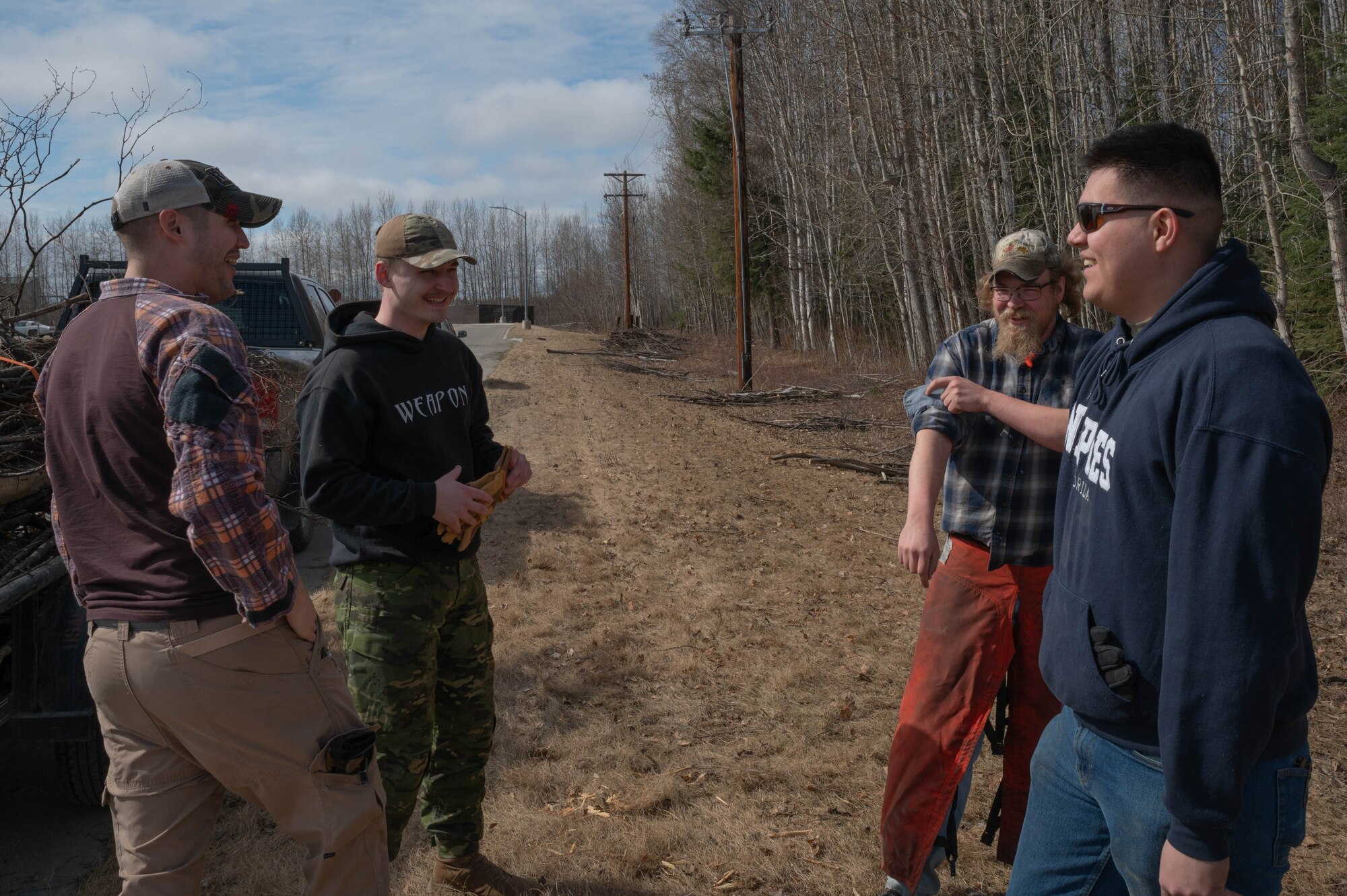 A group of volunteers share a laugh after cleaning up tree branches with the Natural Resources Office at Eielson Air Force Base, Alaska, May 1, 2024.