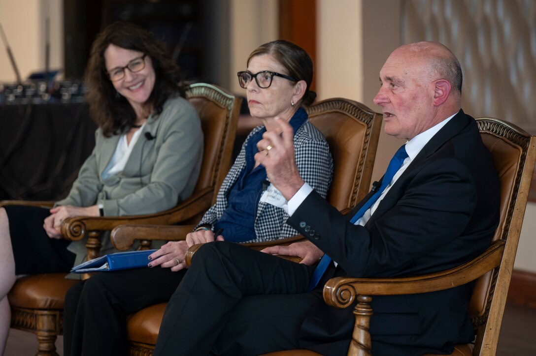 Three white adults sitting in chairs and speaking.