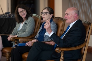 Three white adults sitting in chairs and speaking.