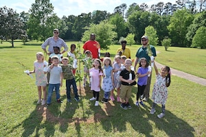 A group of children are accompanied by 14 CES Natural Resources personnel during planting of new heritage tree saplings.