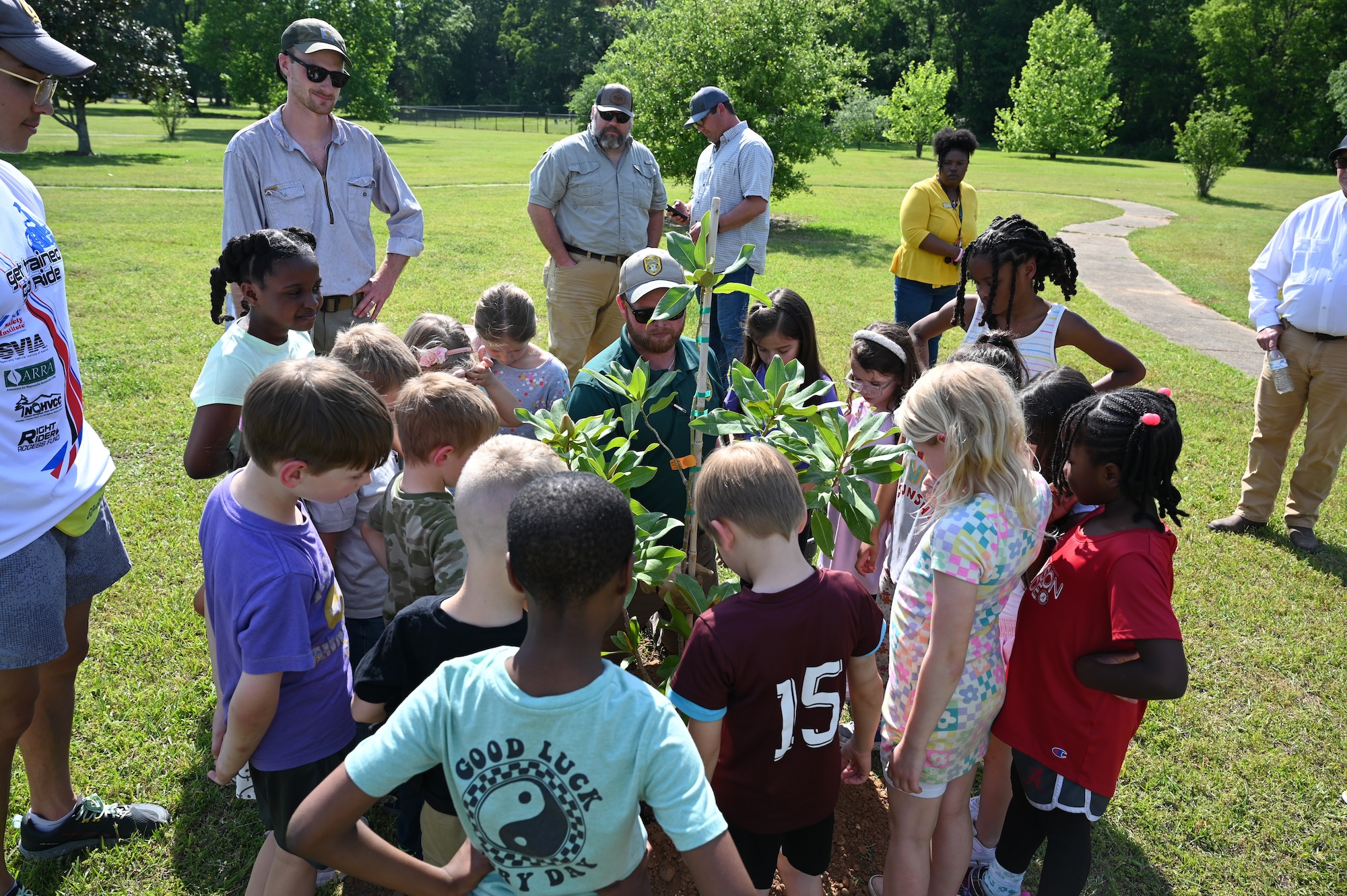 A group of children are accompanied by 14 CES Natural Resources personnel during planting of new heritage tree saplings.