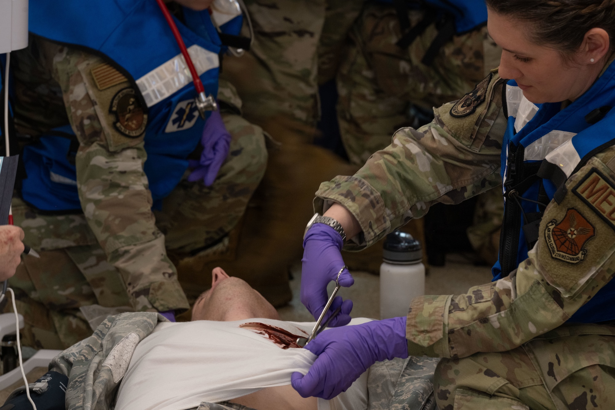 An Airman assigned to the 5th Medical Group (5th MDG) cuts off a patient's shirt during a simulated exercise at Minot Air Force Base, North Dakota, May 8, 2024. The exercise tested the 5th MDG’s readiness to respond to a real-life scenario. (U.S. Air Force photo by Airman 1st Class Trust Tate)