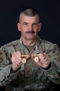 a man hold two gold badges