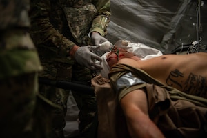 U.S. Air Force Capt. Joshua Wojciechowski, 39th Contracting Squadron contracting officer, has a bandage applied to simulated injuries during Vigorous Warrior 24 at Bakonykúti Training Area, Hungary, May 4, 2024. Vigorous Warrior is NATO’s largest medical exercise, uniting more than 1,600 participants from 33 countries to exercise experimental doctrinal concepts and test their medical assets together in a dynamic, multinational environment. (U.S. Air Force photo by Airman 1st Class Tabatha Chapman)