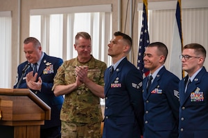 two men applaud three other men while standing during a ceremony