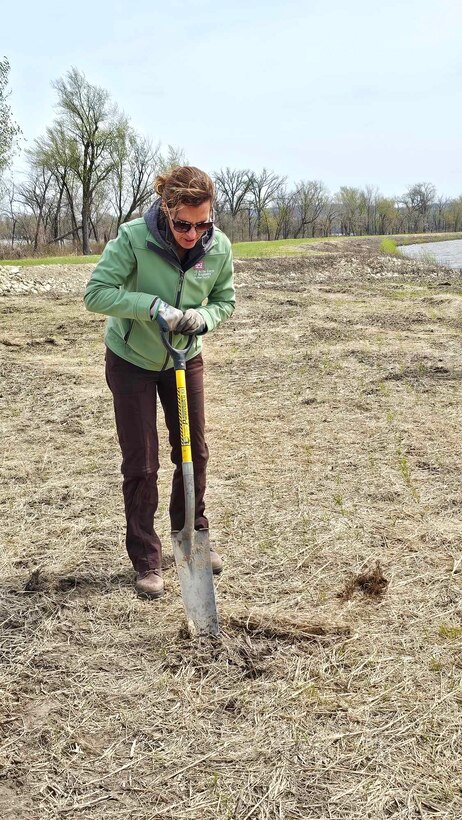A woman digs a hole with a shovel.
