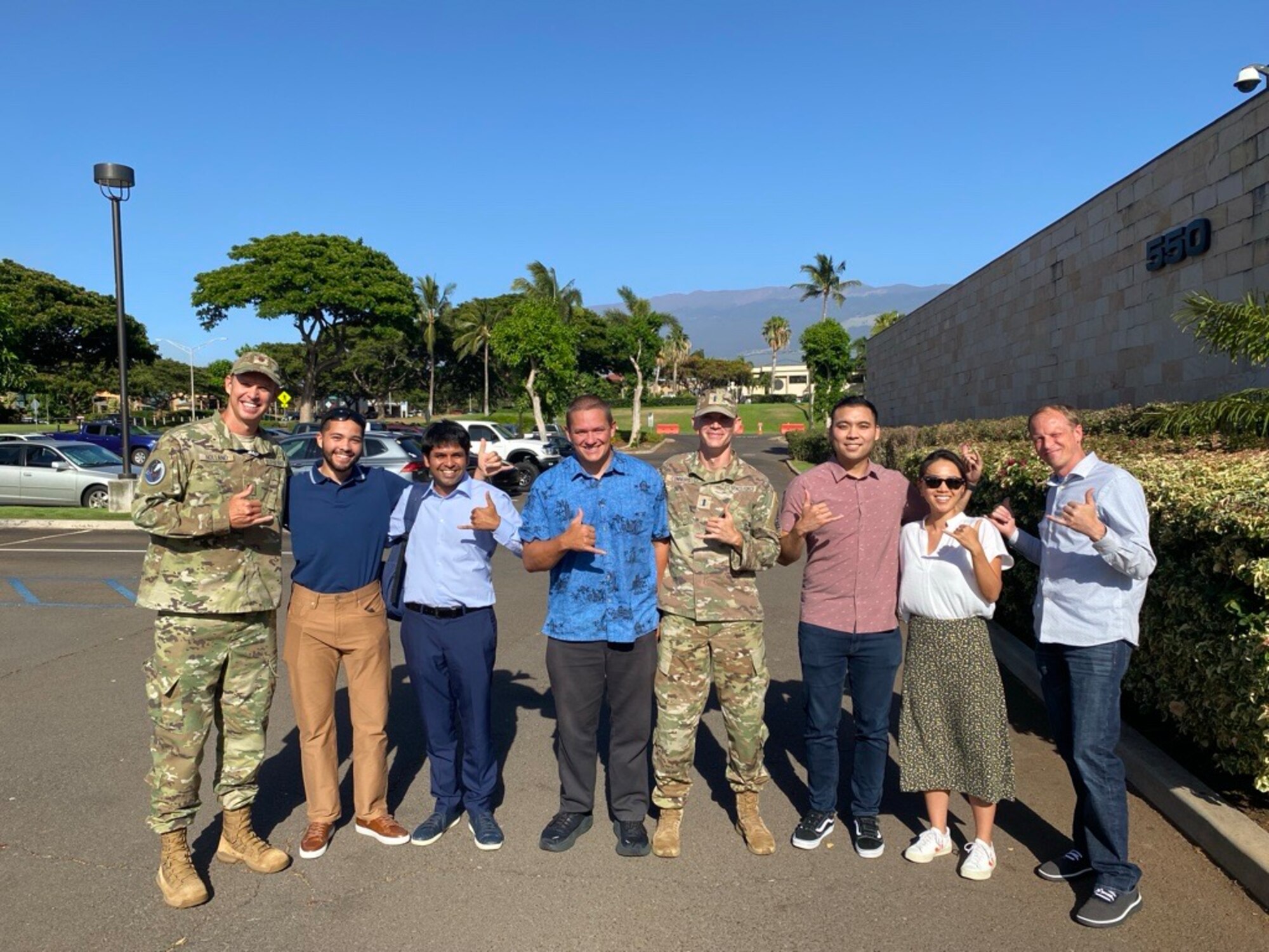 Individuals pose for a photo outside a building in Hawaii.