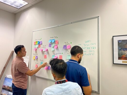  Individuals write on a white board during a collaboration meeting.