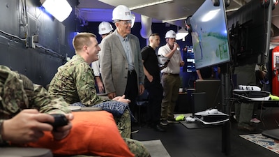 ABHAR John Tice shows a USO representative the new USO gaming space aboard USS George H.W. Bush (CVN 77).