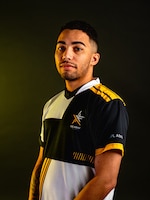 Man with a multi-colored polo standing in front of a black background.