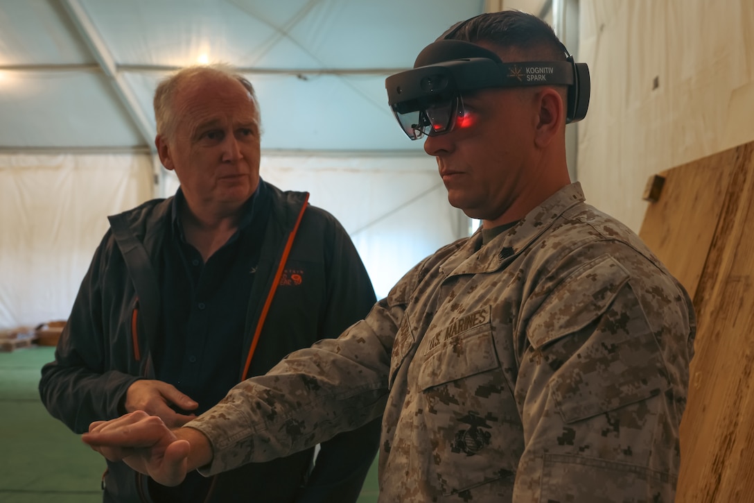 U.S. Marine Corps Master Sgt. Ashton Welborn, right, a ground ordnance weapons chief with Combat Logistics Battalion 13, Combat Logistics Regiment 17, 1st Marine Logistics Group, tests a virtual reality invention developed by Duncan McSporran, founder of Kognitiv Spark and retired British infantry major, at Fort Irwin, California, March 12, 2024. This technology can be used to digitally assess parts and assemblies in a virtual interface prior to production, improving militaries technology. The U.S. Marine Corps and British Army shared expertise in advanced manufactured parts and worked together to refine the NATO repository for joint use. This exchange enables both parties to enhance their own practices and enable digital file interoperability across all NATO militaries. (U.S. Marine Corps photo by Cpl. Casandra Lamas)