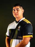 Man with multi-colored polo stands in front of a black background.