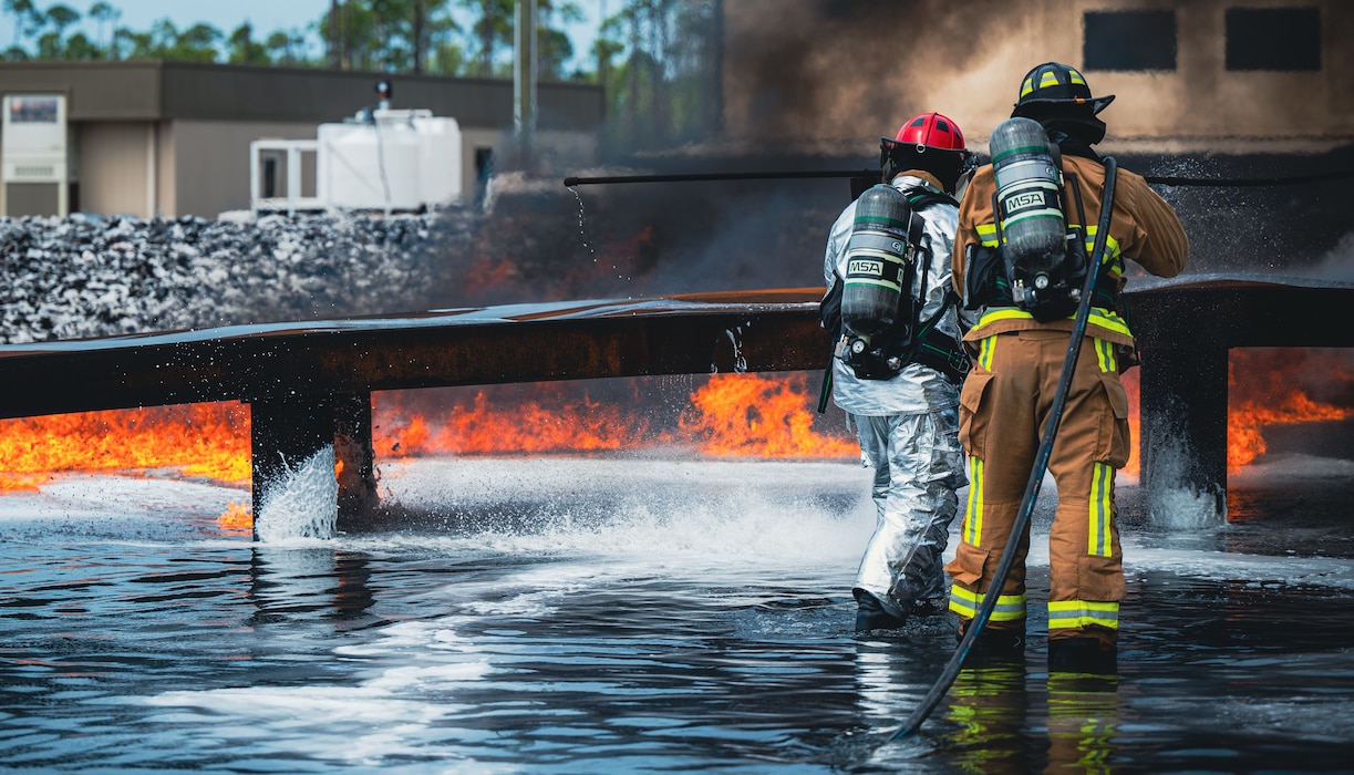Staff Sgt. Christopher Collier, 801st Rapid Engineer Deployable Heavy Operational Repair Squadron Engineers Training Squadron fire protection cadre, and Airman 1st Class Jaremy Wright, 325th Civil Engineer Squadron fire protection firefighter, extinguish a controlled fire