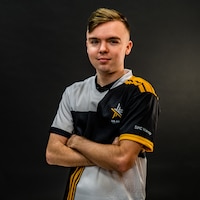 Man with a multi-colored polo stands in front of a dark background.