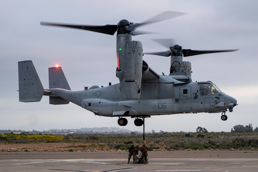 U.S. Marines assigned to Combat Logistics Battalion 15, 15th Marine Expeditionary Unit, sling load cargo beneath an MV-22B Osprey attached to Marine Medium Tiltrotor Squadron (VMM) 165 (Reinforced), 15th MEU, during helicopter support team training on a simulated landing helicopter dock pad at Marine Corps Air Station Miramar, California, May 2, 2024. The LHD pad is a landing zone with dimensions similar to a U.S. Navy amphibious assault ship that allowed the Marines to rehearse the rapid ship-to-shore movement of cargo to expeditionary sites. (U.S. Marine Corps photo by Cpl. Amelia Kang)