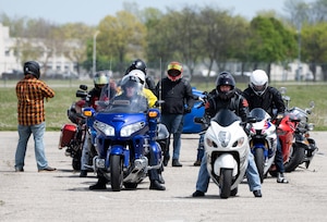 A double line of bikers line up. Riders in full safety gear.