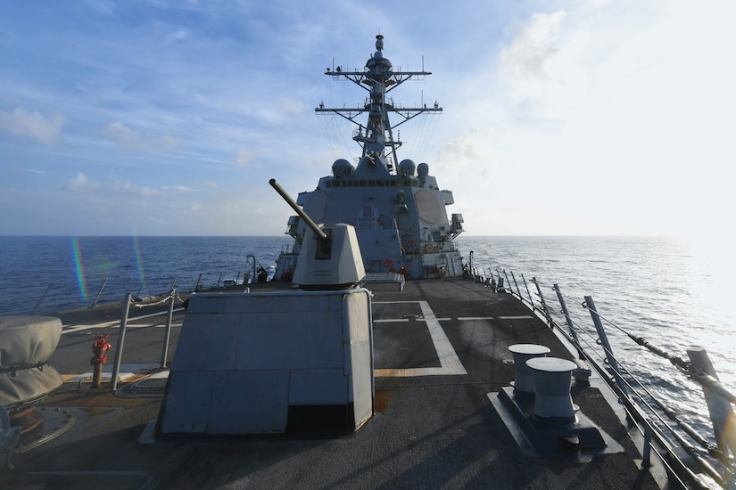 A guided missile destroyer sails in blue water.