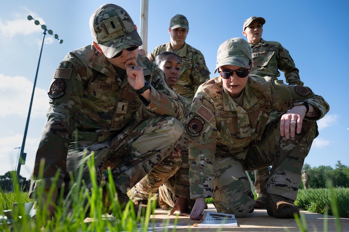 5 airmen look at papers while participating in a readiness day activity.