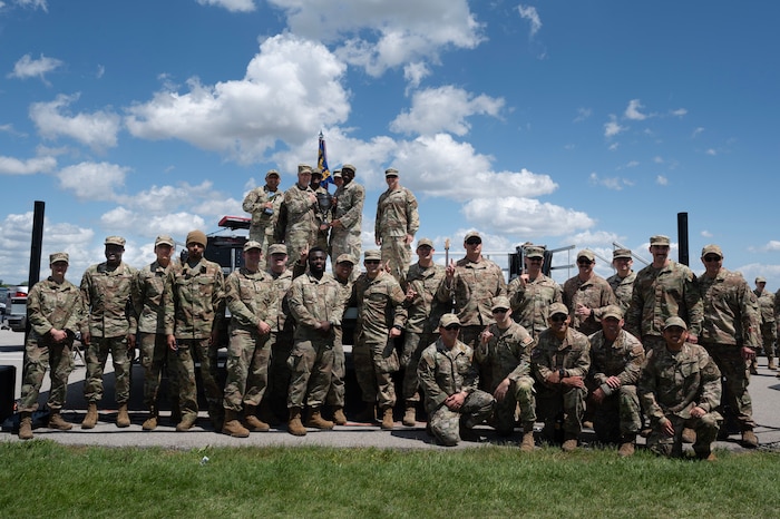 A squadron of airmen pose for photo on a stage.
