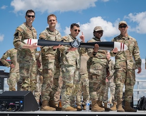 5 airmen pose for photo with awarded historical propeller.