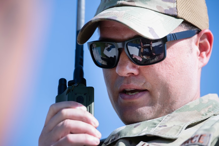 An airmen holds radio and speaks into it.