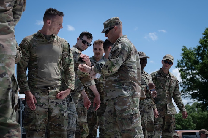 An airmen places a patch onto another Airmen's uniform.