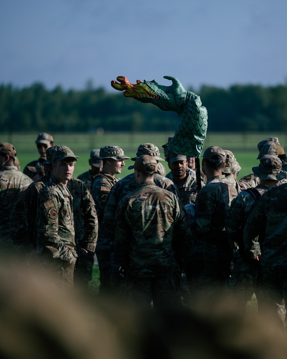 An inflatable dragon is held about a group of airmen.