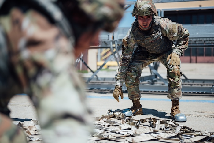 An Airmen wearing OCPs and Battle Rattle adjusts netting on the ground.