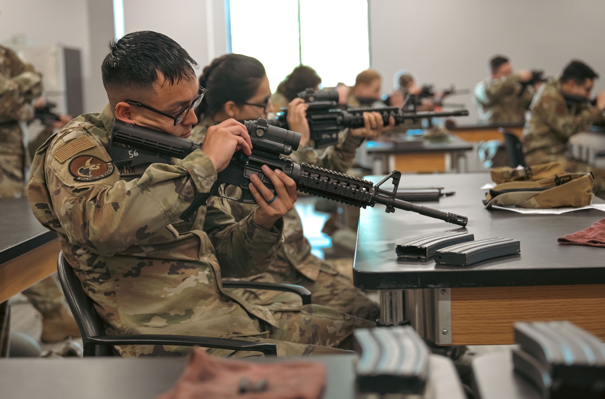 Airman at a desk learning how to operate a gun.